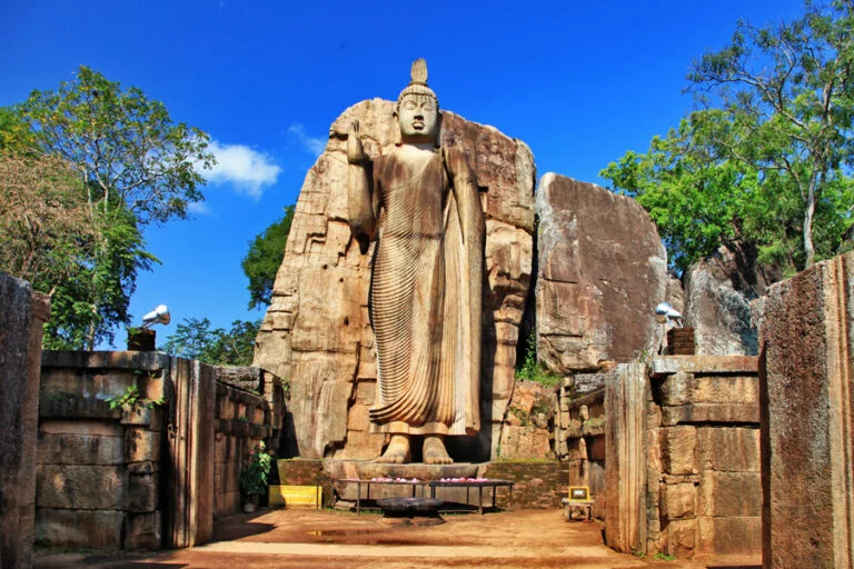 Tượng đá khổng lồ đứng giữa khu di tích và hàng cây xanh