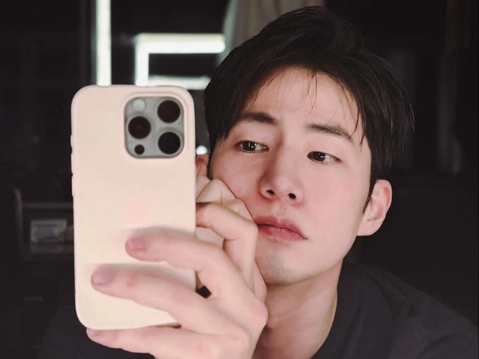 Chàng trai trẻ selfie khoe kiểu tóc Ivy League gọn gàng và phong cách trong không gian tối