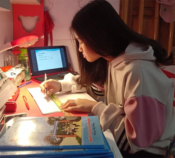 Nữ sinh học bài và sử dụng máy tính bảng tại nhà