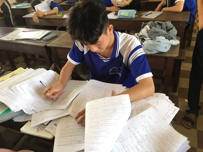 Nam sinh với chồng tài liệu học tập trên bàn