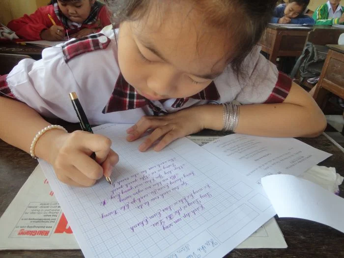 Học sinh tiểu học tập viết chữ trong vở