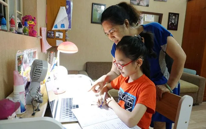 người mẹ đang hướng dẫn con gái học tập