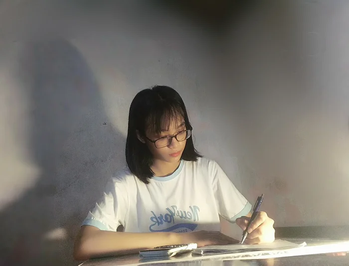 Nữ sinh đeo kính đang tập trung làm bài tập