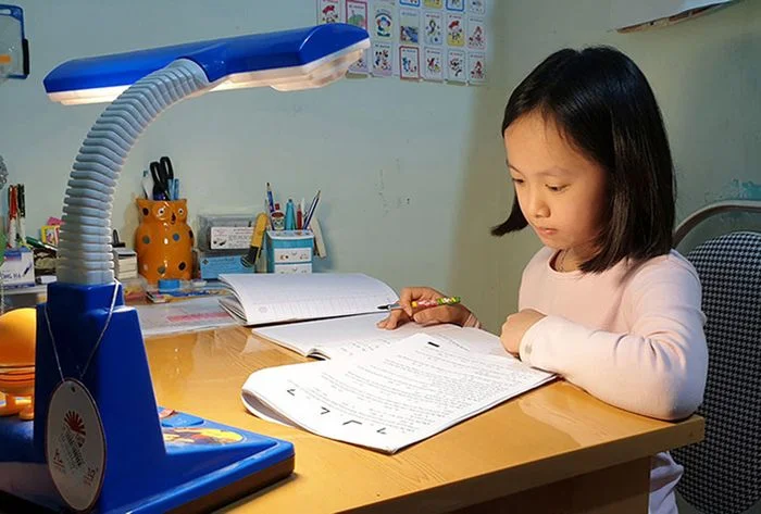 Hình ảnh học tập của một bé gái tại bàn học với đèn chiếu sáng