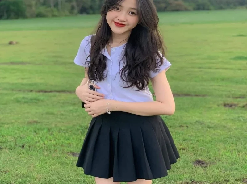 Gái xinh mặc váy đen phối áo sơ mi giữa đồng cỏ
